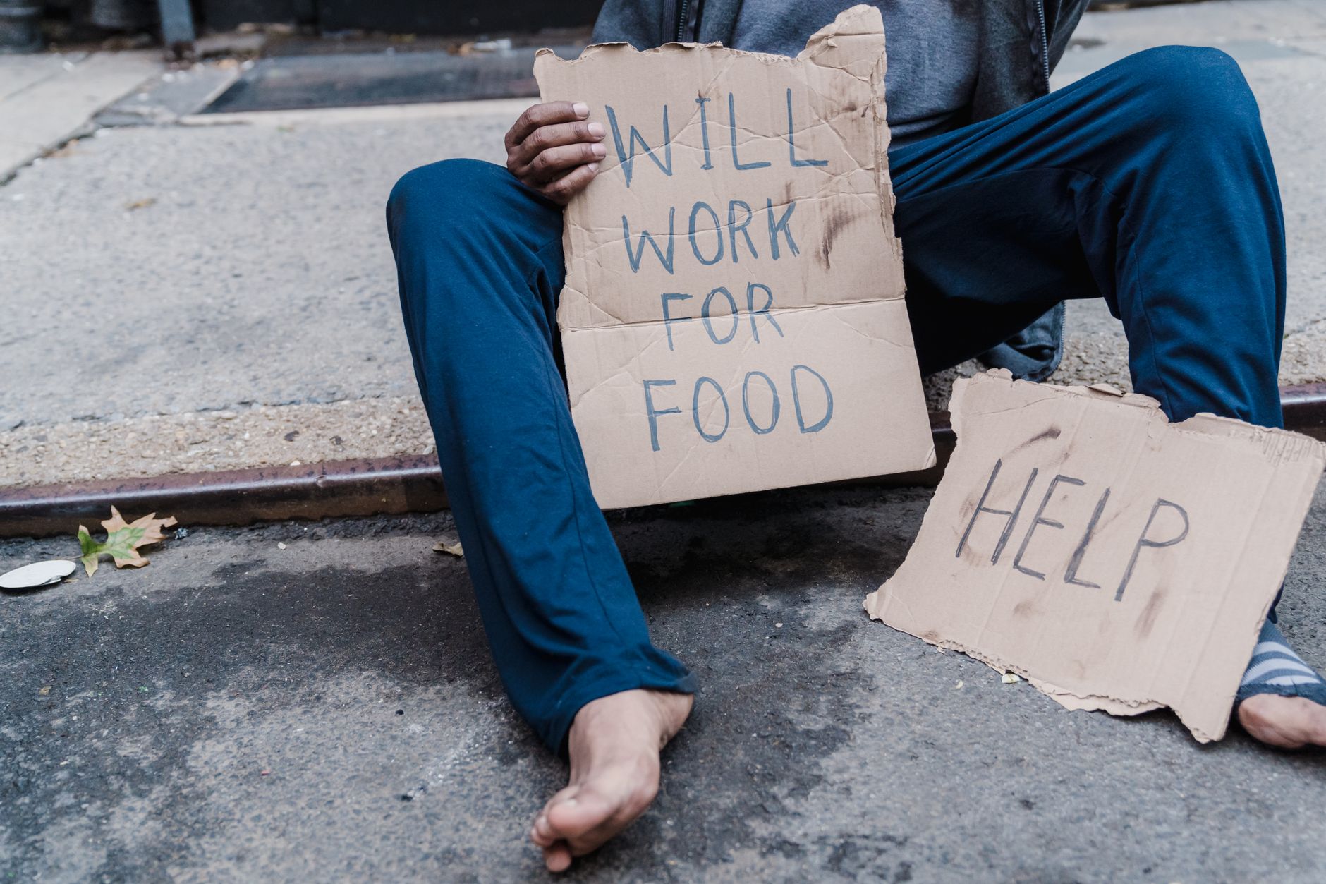 homeless person sitting on the sidewalk
